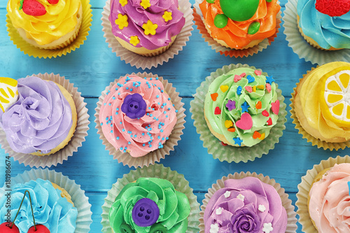 Beautiful cupcakes on color wooden background, top view