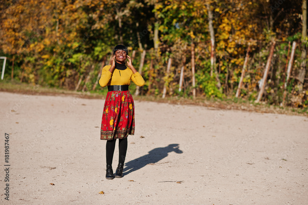 African american girl at yellow and red dress at golden autumn fall park. African american girl at yellow and red dress at golden autumn fall park.