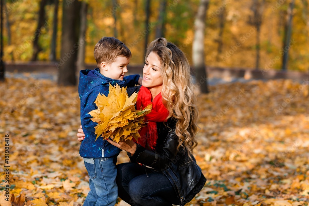 A happy family having fun in the park in autumn walking and hugging. Family, love, happiness concept. mother with her little son hugging A happy family having fun in the park in autumn walking and hugging. Family, love, happiness concept. mother with her little son hugging