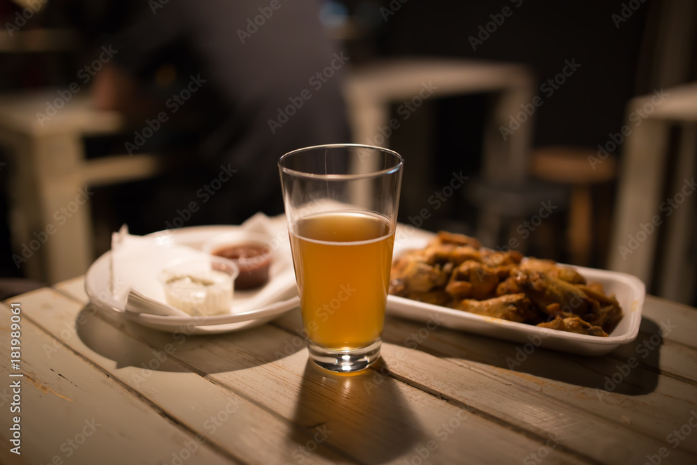 Beer, chicken wings and sauce on a table Beer, chicken wings and sauce on a table