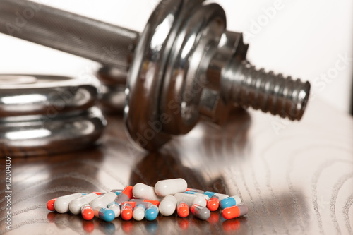 Steroid pills with dumbbell waight in the background - doping in sport photo