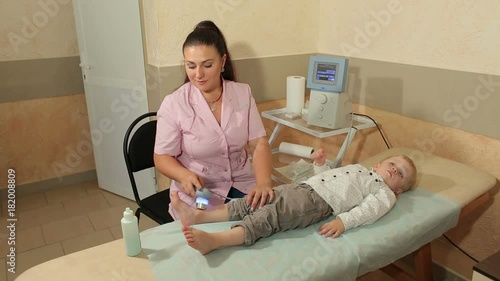 Ultrasound treatment for feet the small kid in the physiotherapy room. A small child lies on a couch in a modern clinic. photo