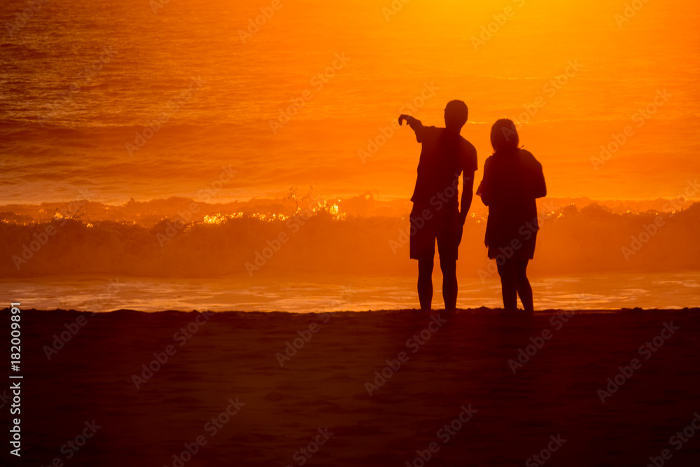 silhouetted couple loverlooking sunset washed waves