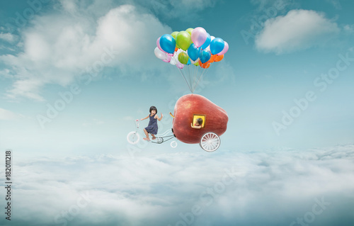 Happy sister enjoy with fantasy apple cycle ride  and floating in sky with bunch of colorful balloons .