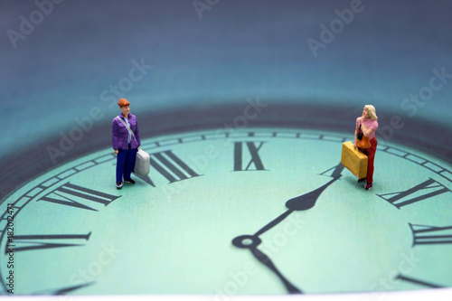 Miniature people : couple traveller standing with clock