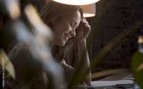Young beautiful business woman sitting at table and laughing with closed eyes