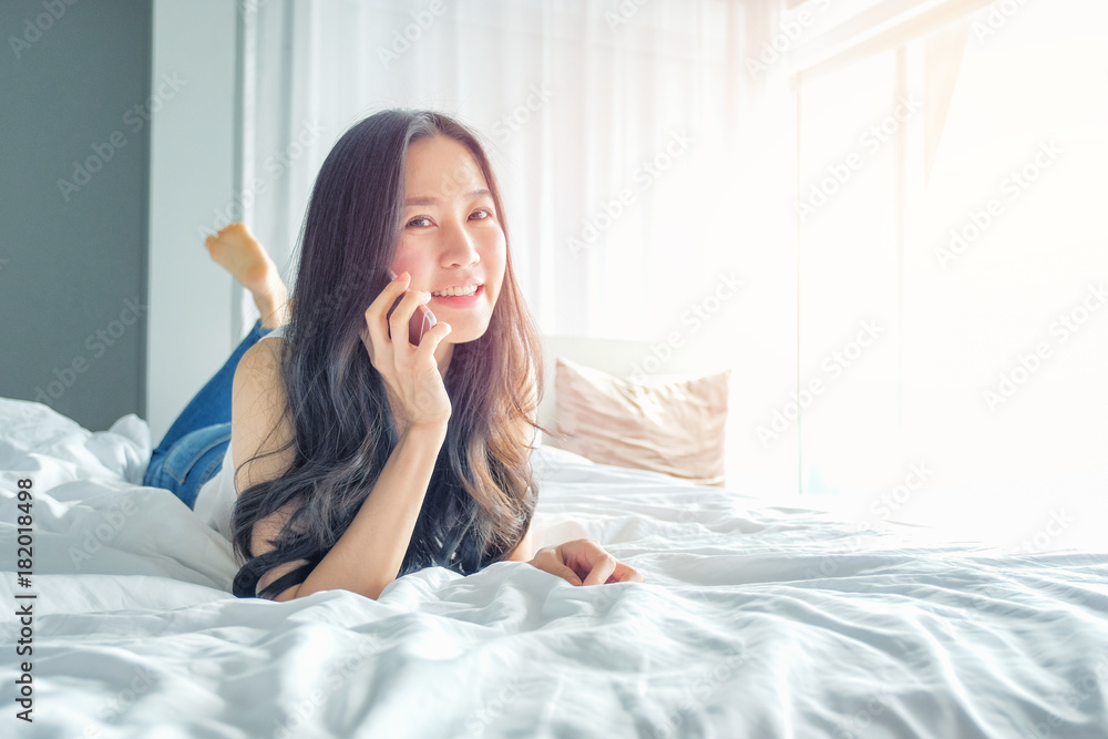 Young beautiful woman lying on the bed and talking on the phone Young beautiful woman lying on the bed and talking on the phone
