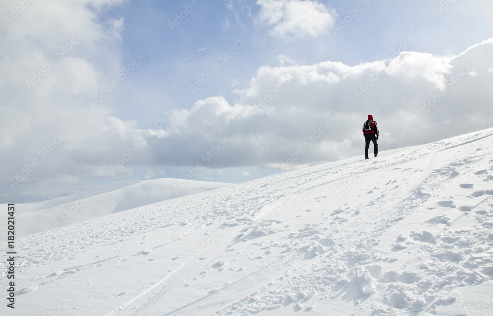 Man hiking up the snow-covered slope in Carpathian, Ukraine.
