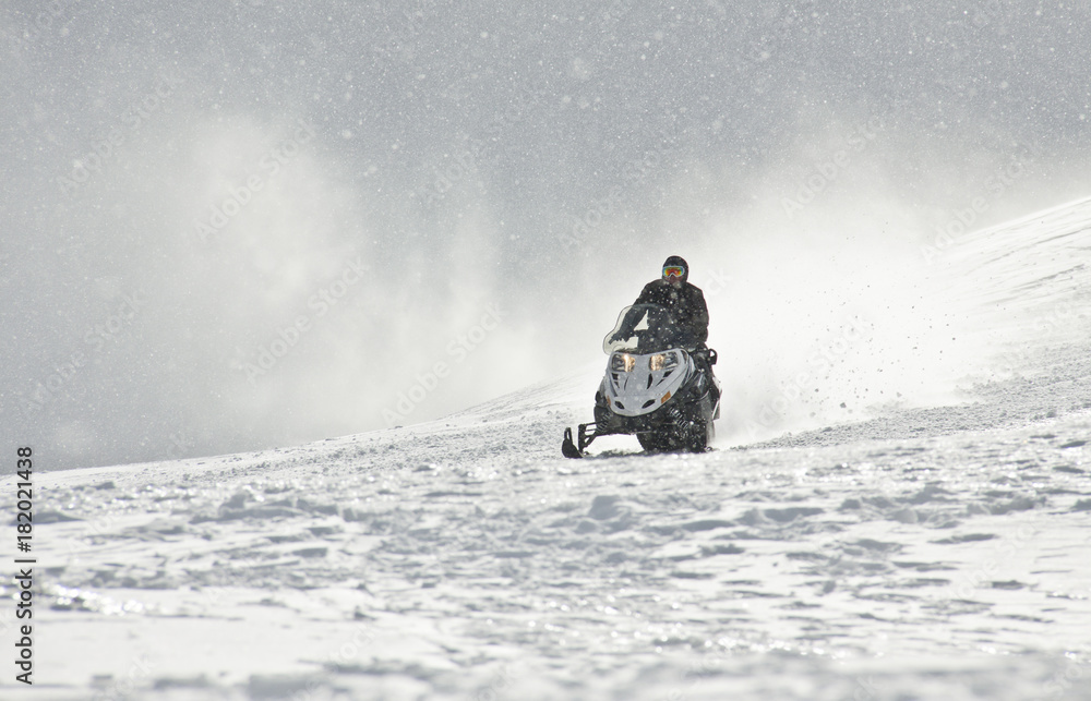 A man driving sports snowmobile in mountains.