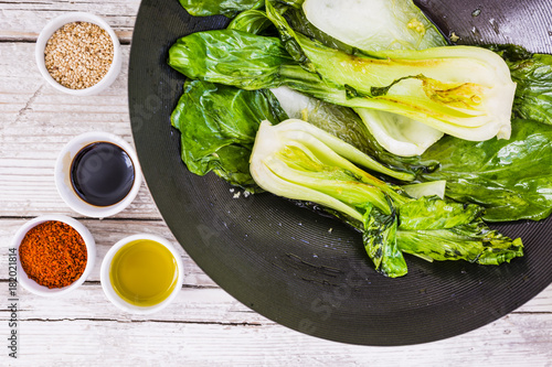 Fried Chinese cabbage Pak Choi and cooking ingredients on wooden background.