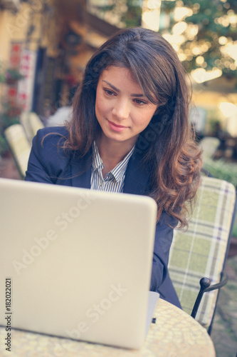 Business woman working on laptop at cafe.