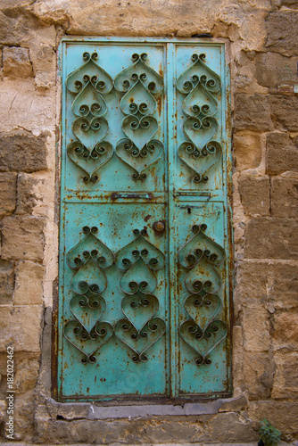 green door with heart patterns. historical iron door on stone building. metal doorknob on green door.  photo