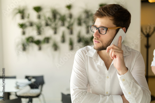 Pensive young businessman in cafe using phone