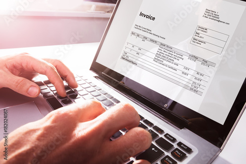 Businessman's Hands Working On Invoice On Laptop photo