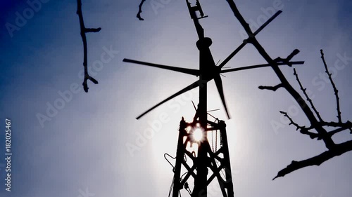 Wind Turbine with Hand Silhouetted by the Sun in Blue Sky. 4K UltraHD video.