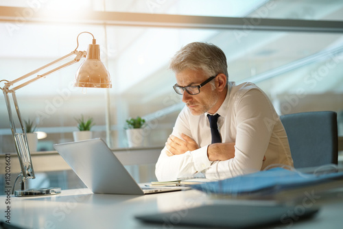 Businessman working on laptop in office, being concerned