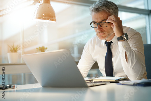 Obraz na plátně Businessman working on laptop in office, being concerned