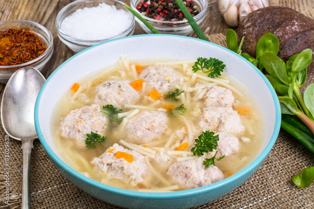 Soup with meatballs for dinner on wooden background