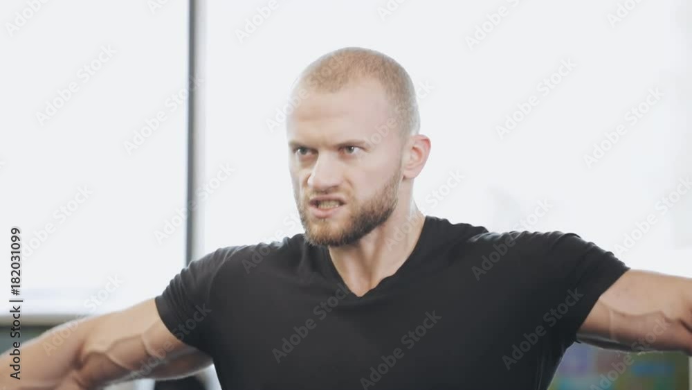 Man lifts a dumbbell in gym, he pumping deltoid muscles