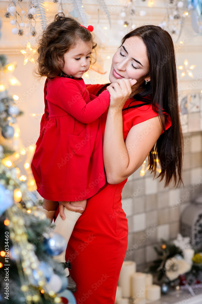 Merry Christmas celebration. Beautiful family in a red dresses near the Christmas tree. Christmas miracles. Happy New Year Merry Christmas celebration. Beautiful family in a red dresses near the Christmas tree. Christmas miracles. Happy New Year