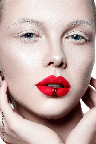 Beautiful woman portrait with white skin, red lips and hands on face.