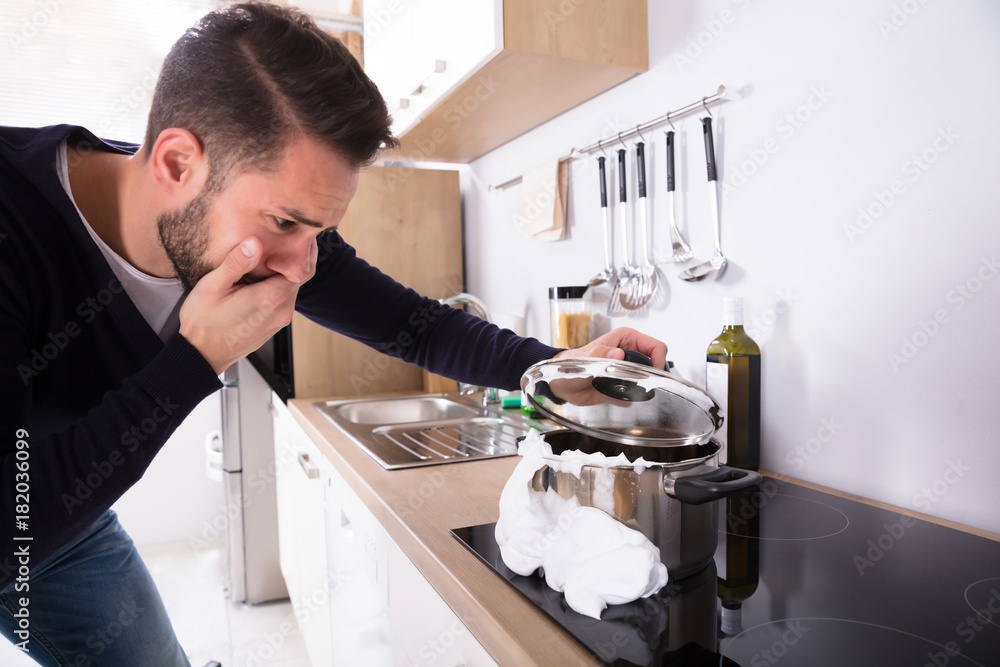 Man Looking At Spilling Out Boiled Milk From Utensil Stock Photo