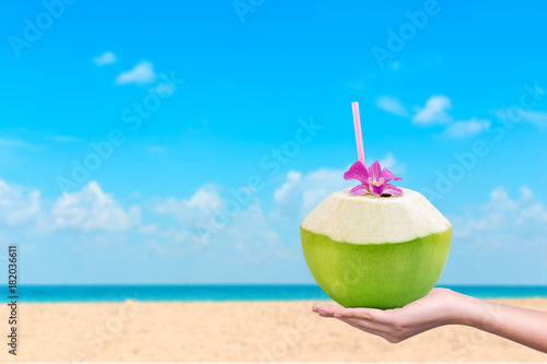 Hand holding fresh coconuts with drinking straw and copy space background