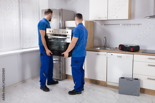 Two Men Fixing Oven In Kitchen photo
