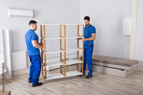 Two Men Holding Shelf In Living Room