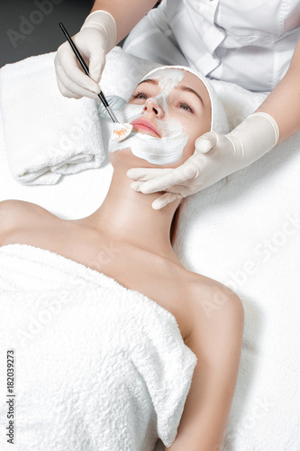 beautician applies mask to the face of woman 