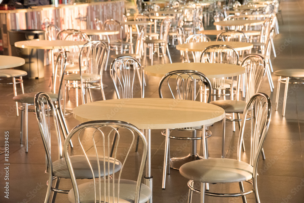 Metal chairs with high backs and tables in the morning sun in the cafe