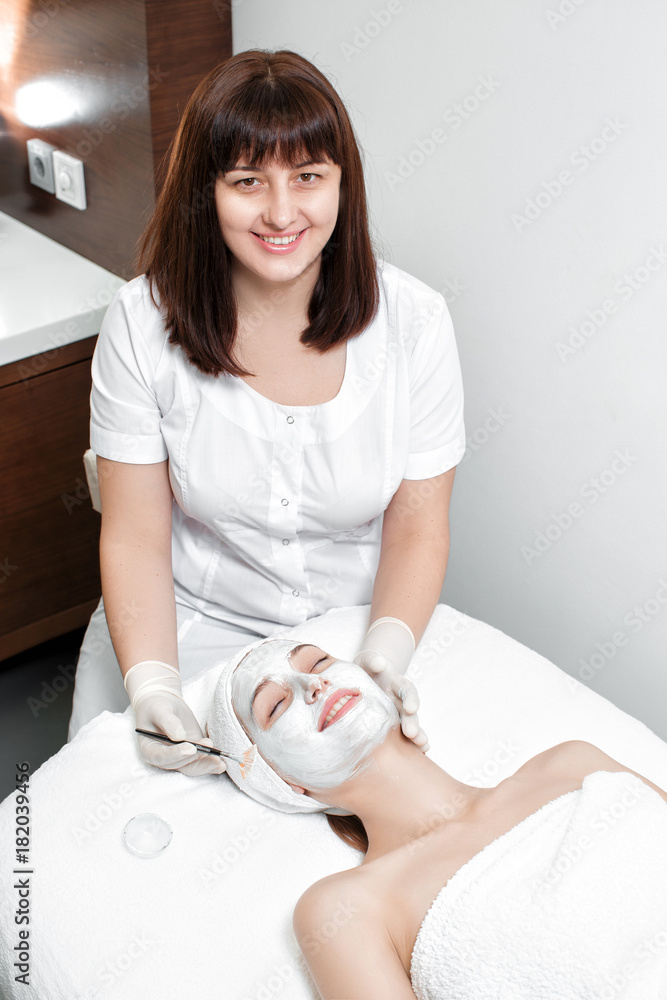 beautician applies mask to the face of woman beautician applies mask to the face of woman