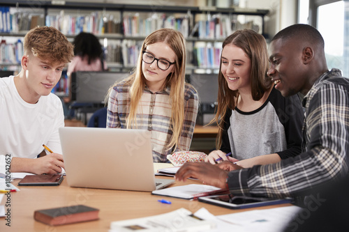 Group Of College Students Collaborating On Project In Library