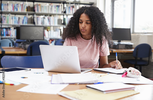 Female Student Working At Laptop In College Library