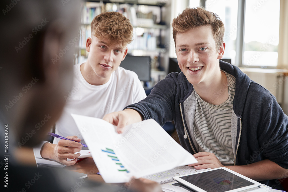 Fototapeta premium Three Male College Students Collaborating On Project In Library