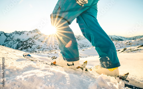 Legs of professional skier at sunset on relax moment in french alps ski resort - Winter sport concept with adventure guy on mountain top ready to ride down - Side view point with azure vintage filter photo