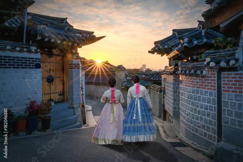 Photography Back of two women wearing hanbok walking through the traditional style houses of Bukchon Hanok Village in Seoul, South Korea
