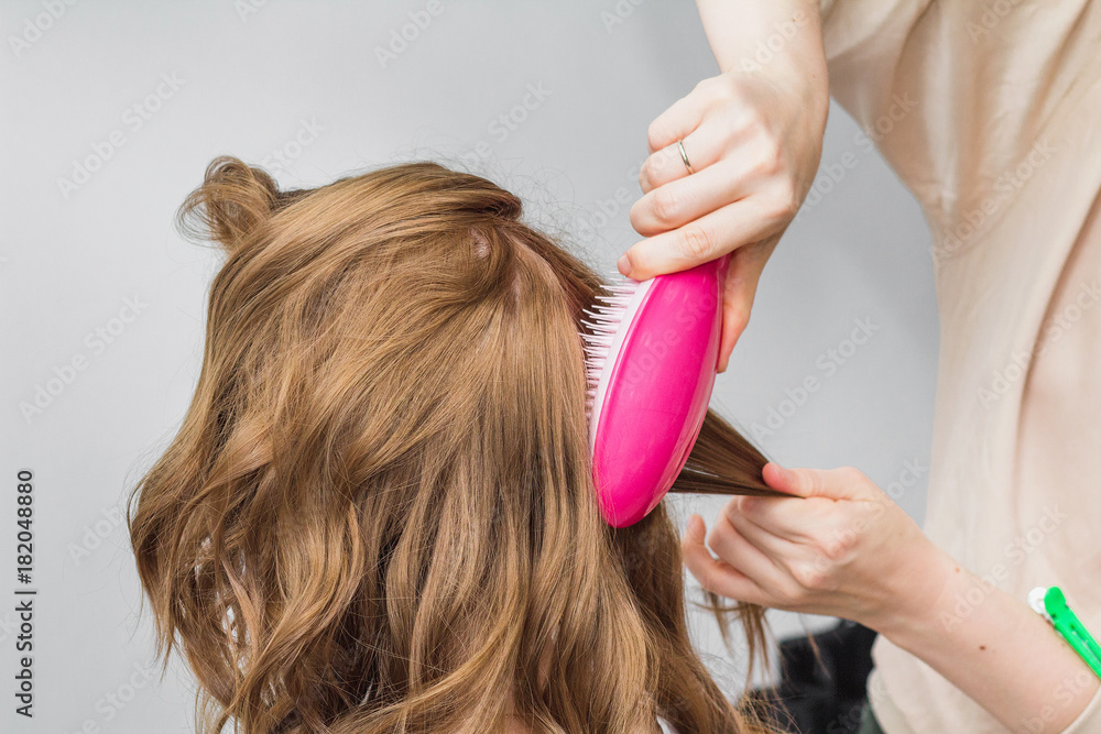 hairdresser making preparation for a ginger woman in a beauty salon combing her hair with brush hairdresser making preparation for a ginger woman in a beauty salon combing her hair with brush