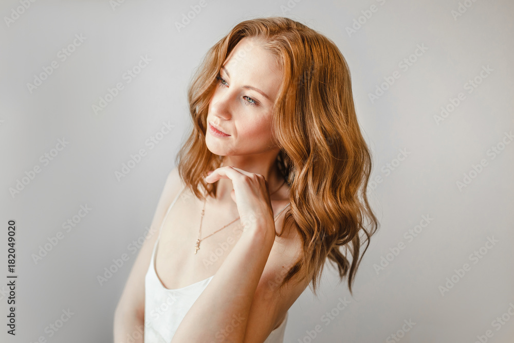 Ginger woman with wavy volumetric hair styling at white background Ginger woman with wavy volumetric hair styling at white background
