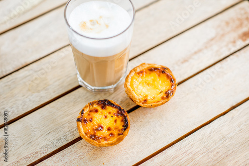 Portuguese coffee galao with sweet dessert pastel de Nata on the table outdoors photo