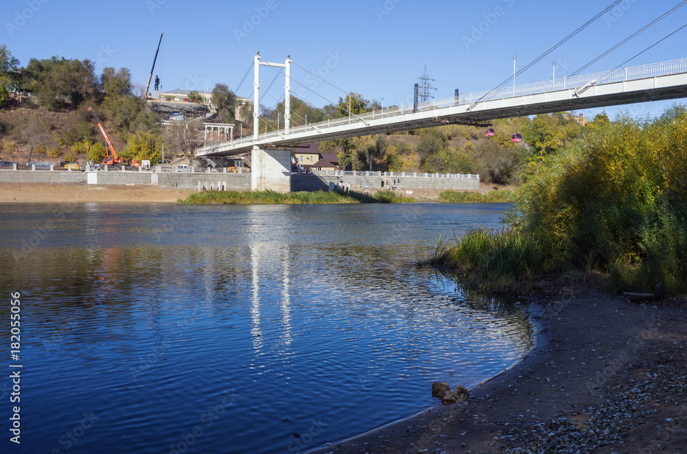 The shore of the Ural River, the pedestrian bridge, embankment / The picture was taken in Russia, in Orenburg. 10/10/2017