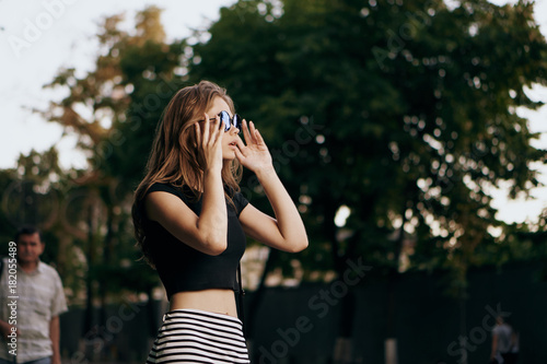 Young beautiful woman in sunglasses and striped skirt outside in the city