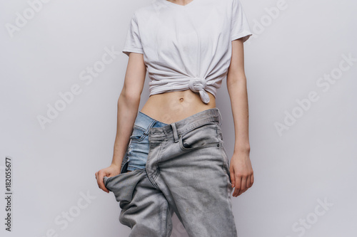 Quadro em tela Woman in big pants on a gray background, fitness, slender waist, slenderness
