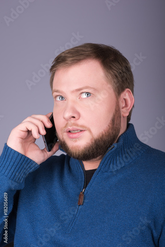 Young man with beard talking on the phone. The gaze is directed upwards