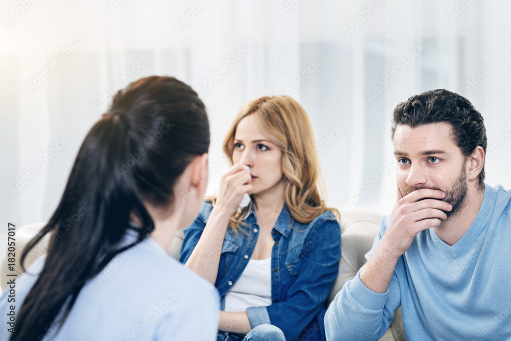 Help us. Thoughtful unhappy young couple visiting a psychologist and hoping for help while having problems in their relationships Help us. Thoughtful unhappy young couple visiting a psychologist and hoping for help while having problems in their relationships