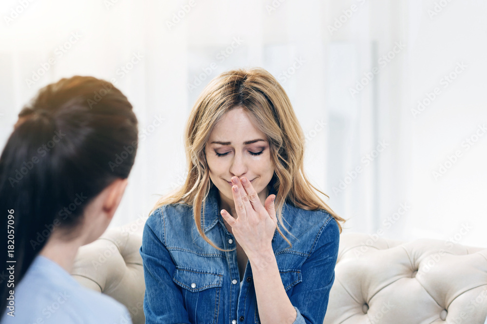 Professional therapy. Cheerless upset attractive woman visiting a psychologist and sharing her problems while hoping for help Professional therapy. Cheerless upset attractive woman visiting a psychologist and sharing her problems while hoping for help