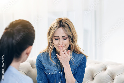 Professional therapy. Cheerless upset attractive woman visiting a psychologist and sharing her problems while hoping for help