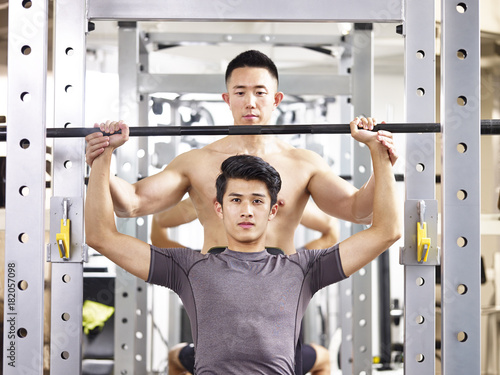 young asian man lifting weight in gym