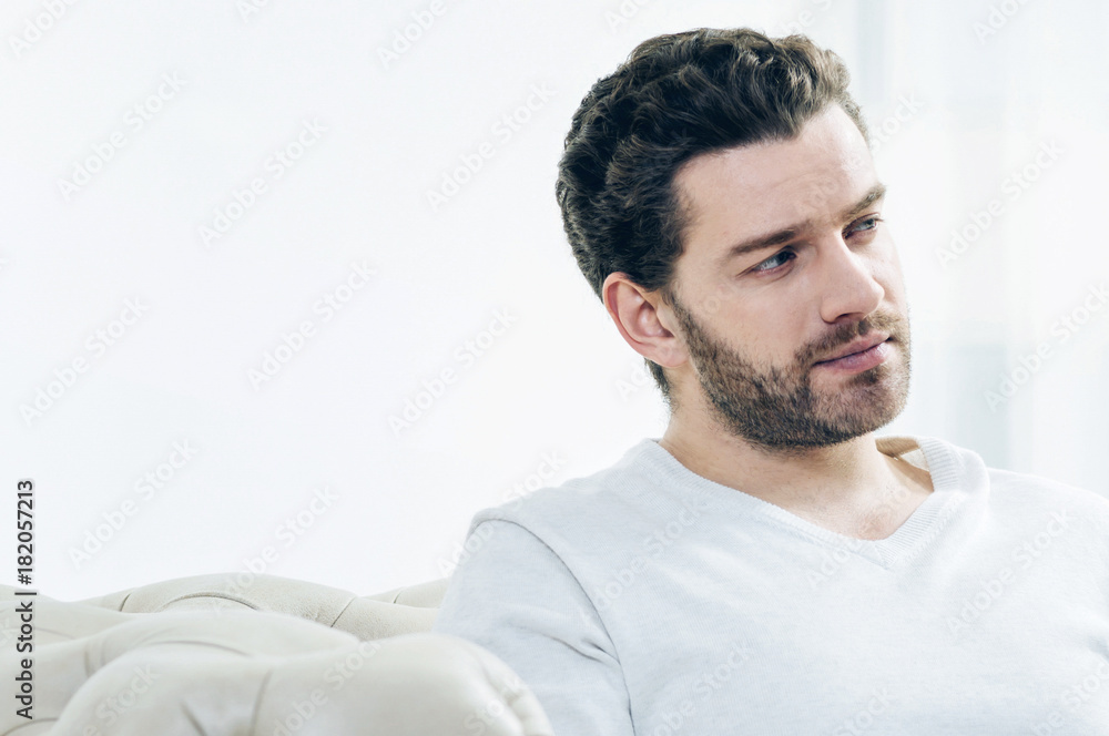 Handsome man. Portrait of a pleasant nice bearded man while sitting on the sofa and thinking about his life Handsome man. Portrait of a pleasant nice bearded man while sitting on the sofa and thinking about his life