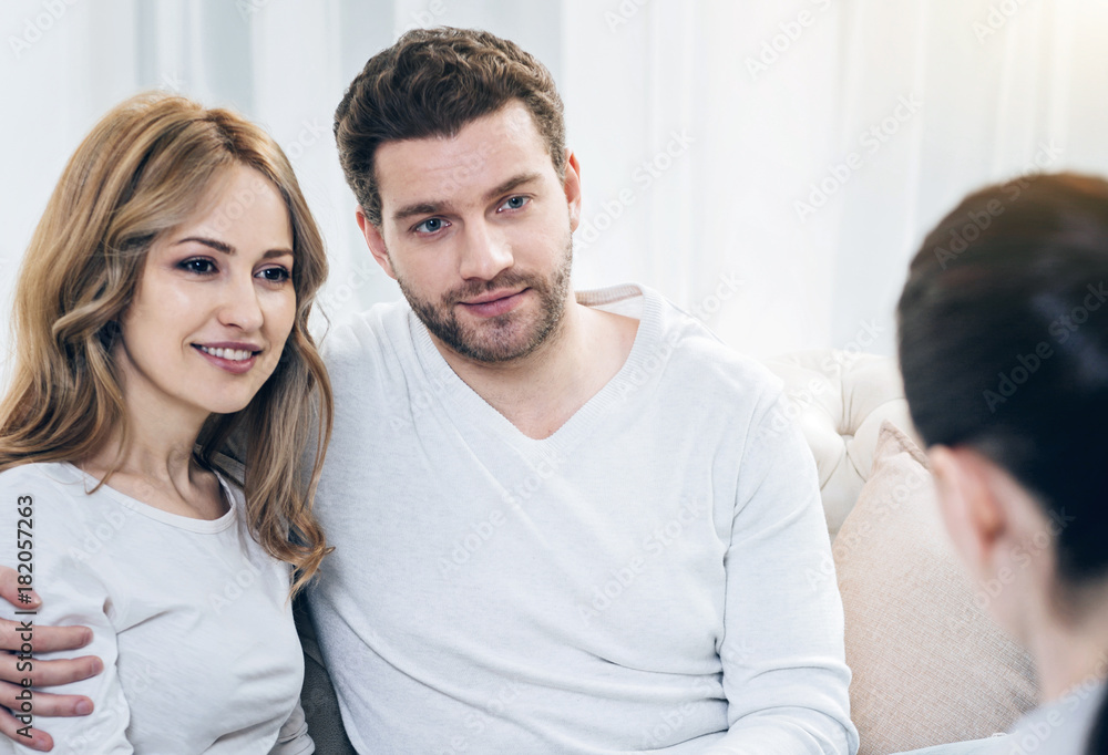 Obraz premium Overcoming problems. Joyful nice positive couple sitting together and looking at their therapist while feeling happy